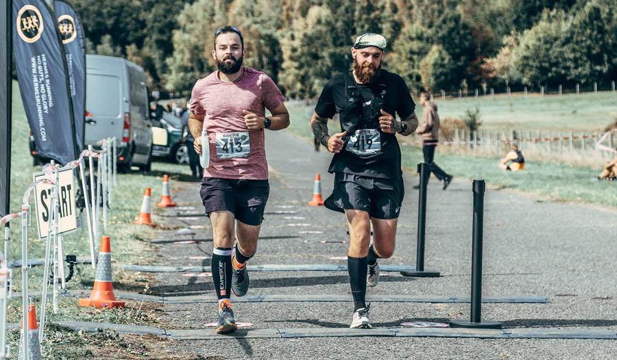 running event with two men running side by side with numbers on shirts.