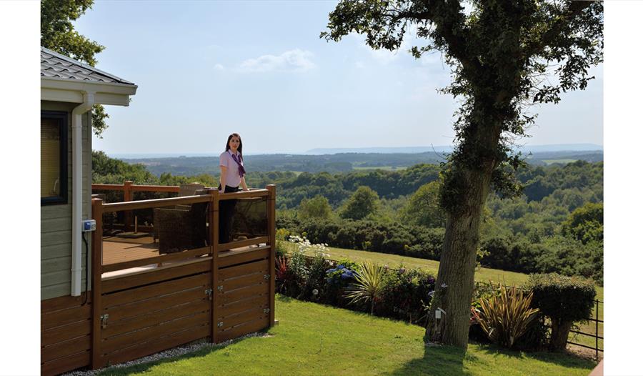 Woman standing on lodge decking enjoying the view  at Crowhurst Park East Sussex