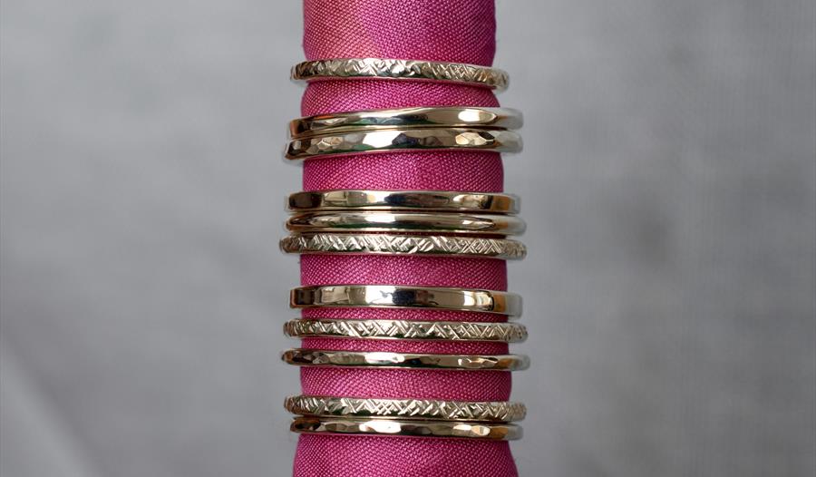 photograph of silver rings stacked together placed through pink linen roll.