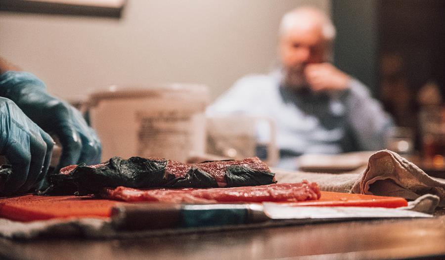Photograph of a meat being prepared in a pub setting.