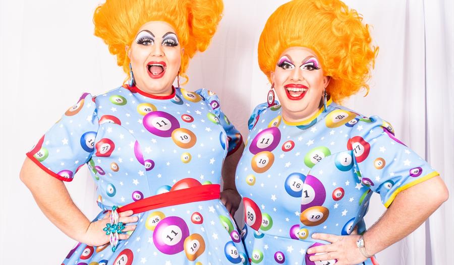 two drag artists wearing colourful dresses