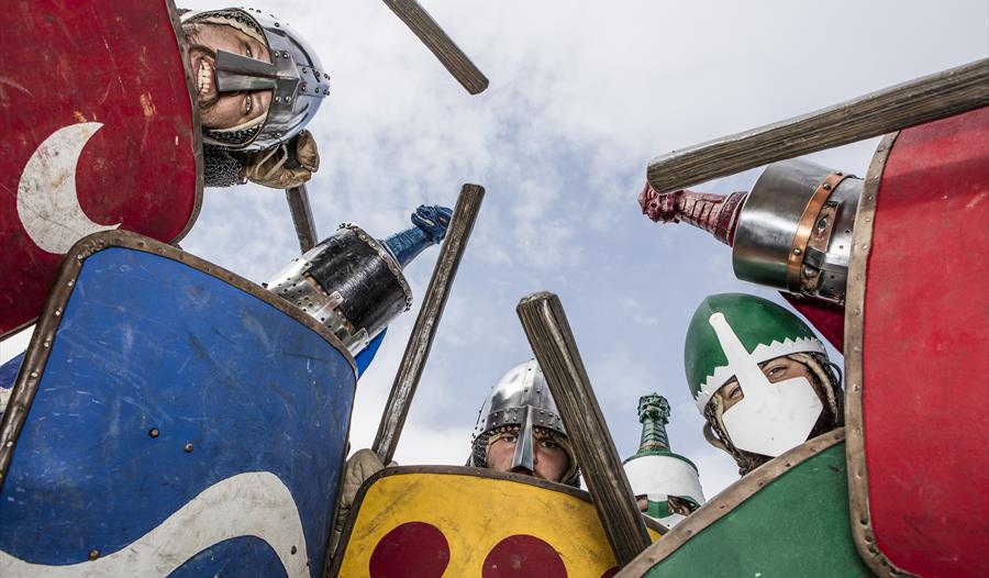 view from ground up as knights with sheids look down into the camera.