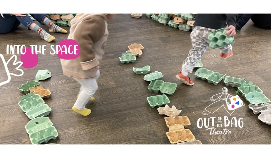 Children navigating a winding trail of recycled cardboard egg cartons during an interactive theatre play session