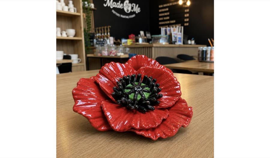 Handcrafted clay poppy displayed on a table in a pottery studio, created as part of a poppy-making workshop.