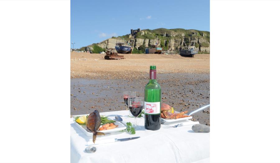Seafood and wine set on Hastings beach with fishing boats and cliffs behind at the Seafood and Wine Festival.