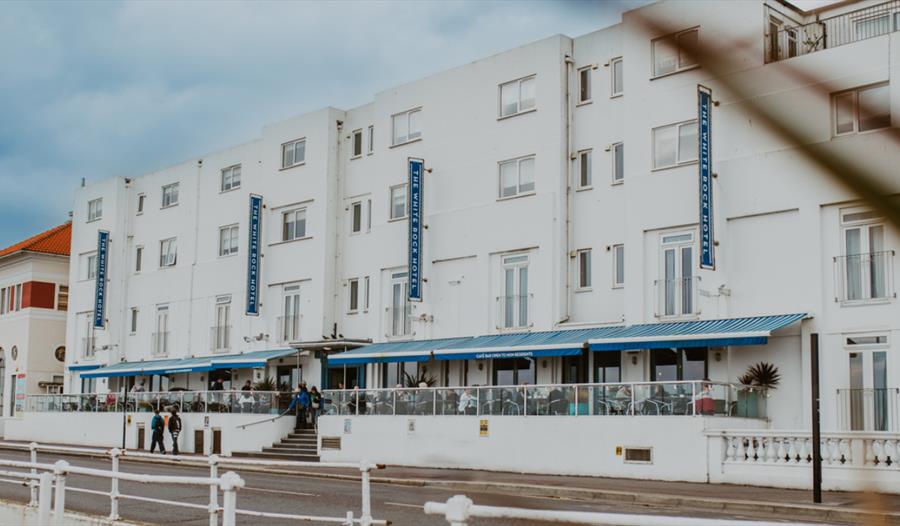 Exterior view of The White Rock Hotel in Hastings with outdoor seating along the seafront promenade.