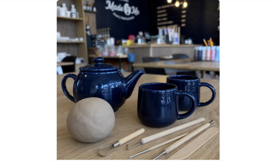Clay, cuppa and creativity: pottery tools, clay and tea set ready for a relaxed clay-making workshop.