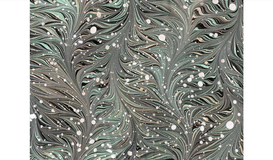 Green and black marbled pattern with flowing feather-like swirls and scattered white spots.