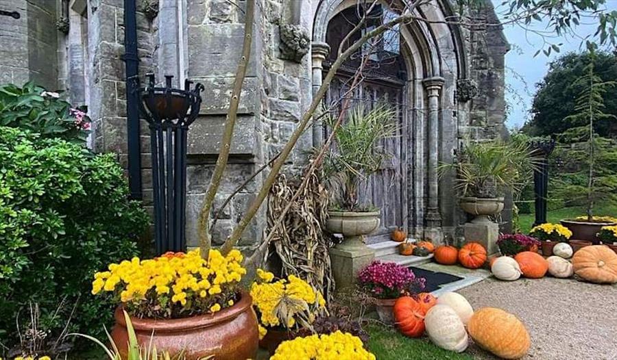 outside porch of an old stone building with flowers and pumpkin display.