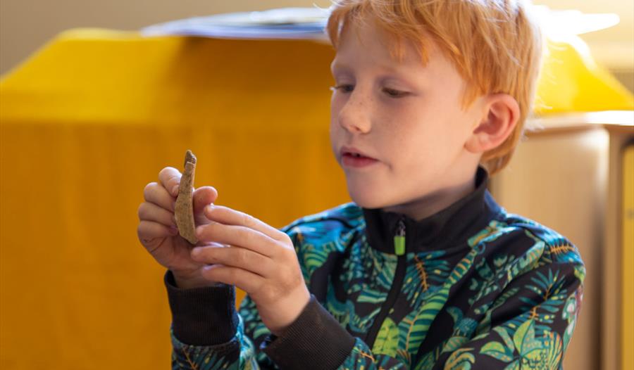 young boy inspecting small archaeological object