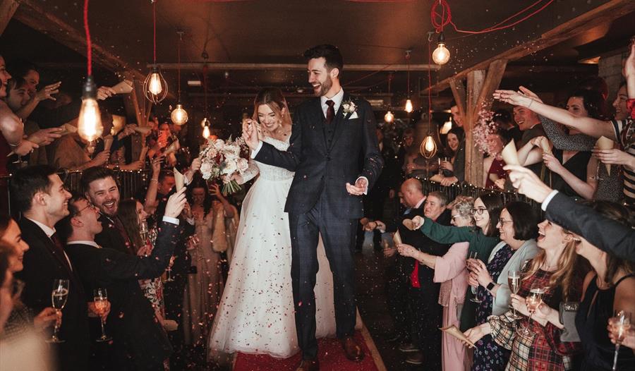 photograph of newly married couple being showered in confetti.