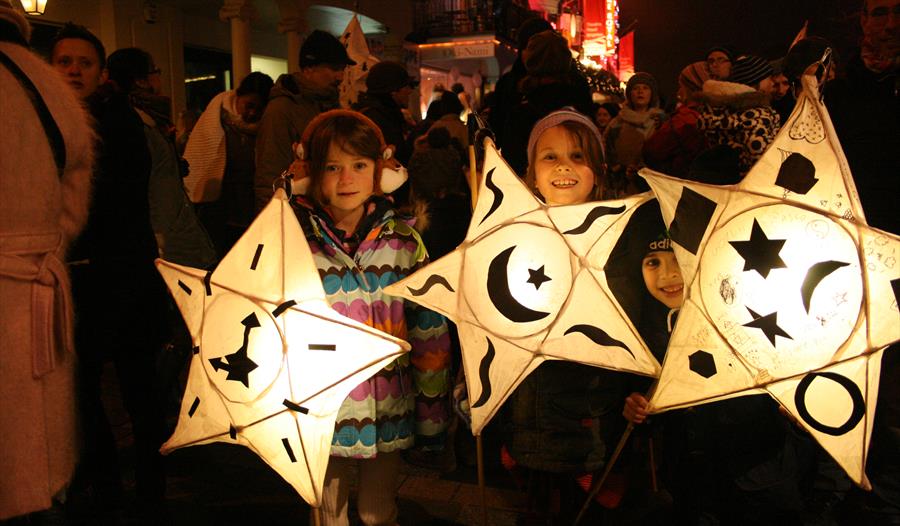 three children holding paper lanterns in the shape of stars