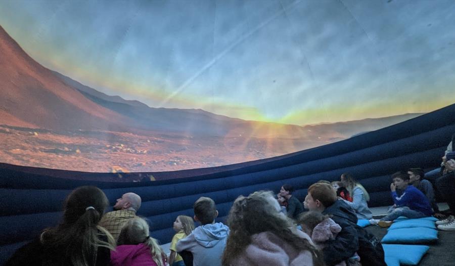 children sitting inside a planetarium