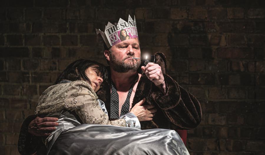 close up of stage performance. Man with paper crown holds lady in his arms