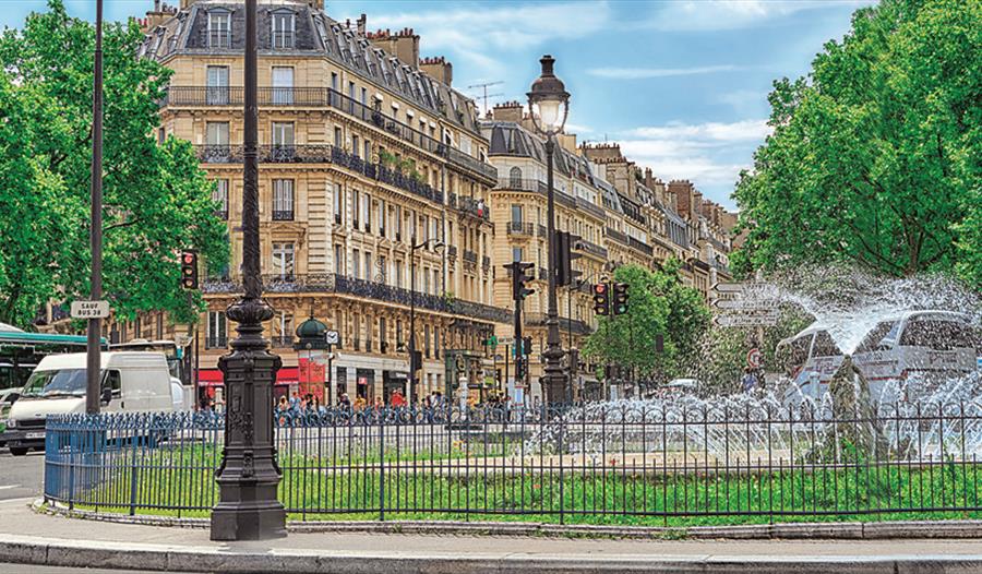a photograph of a city street. High terraced houses with fountain in foreground.