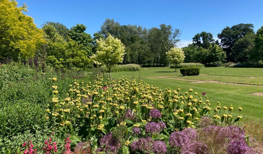 wide flower border with lawn at michelham priory.