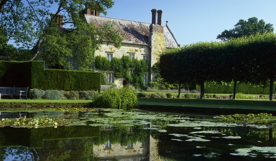 View of square pond and rural house a hedgerows