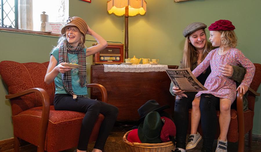 children and mum sat in 50s-style living room wearing hats.