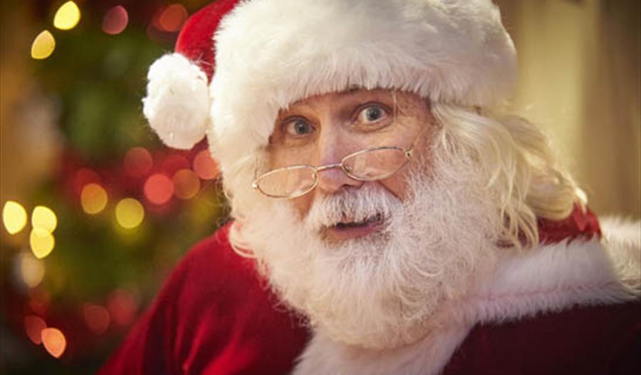 a close up of Father christmas with blurred fairly lights in the background.