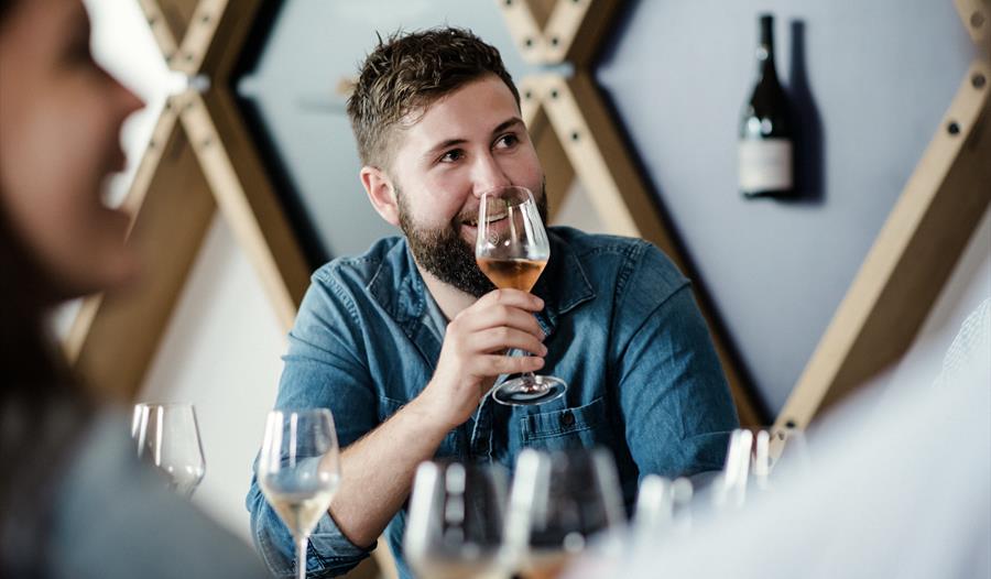 a white man with a raised wine glass, sat at a table.