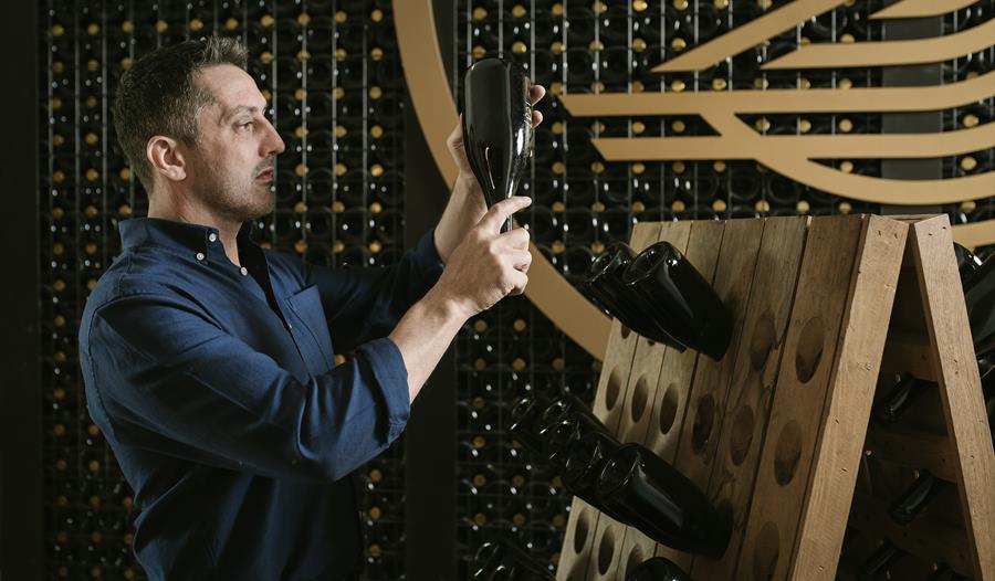 Man inspecting a bottle in a wine cellar.