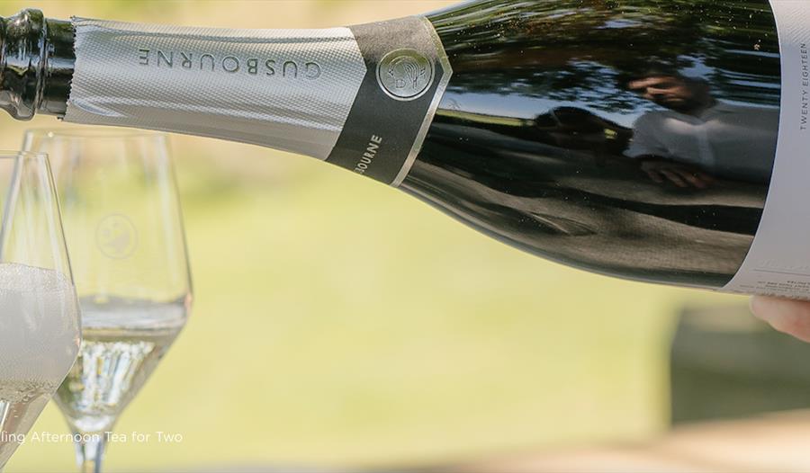 Bottle of Gusbourne sparkling wine being poured into two flutes