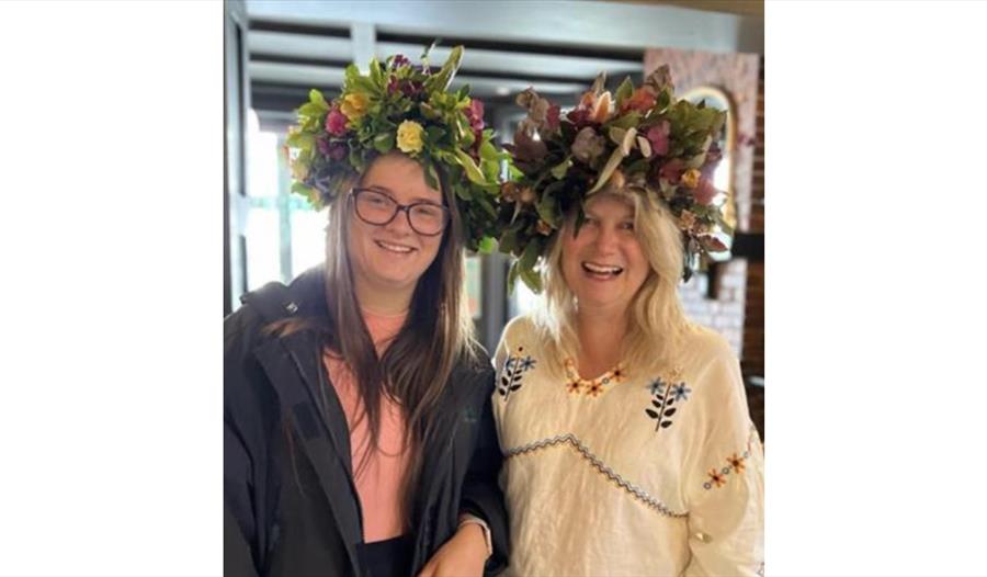 Image shows picture of 2 people wearing flower crowns at Jack in the Green