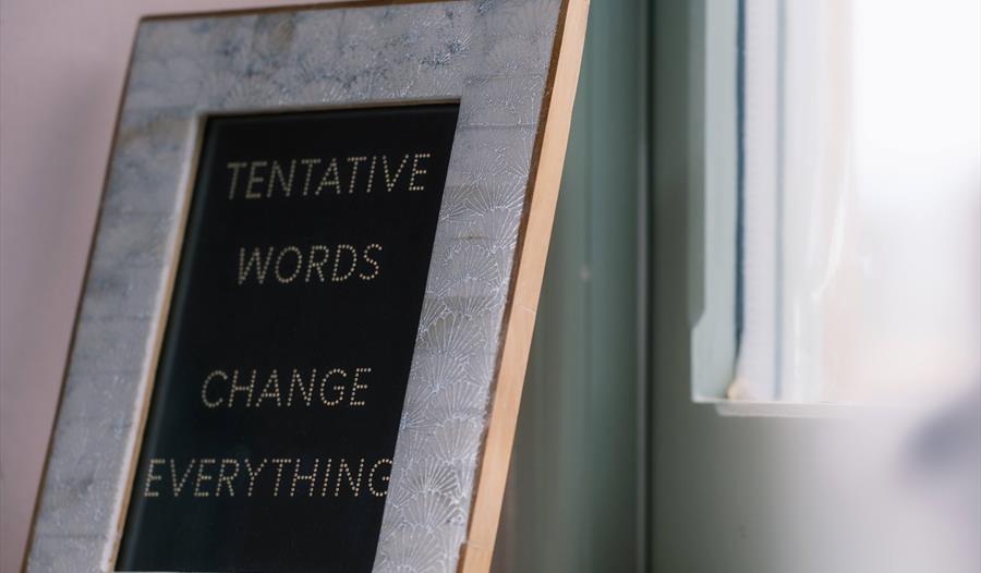 picture frame with text within stating 'tentative words change everything'.