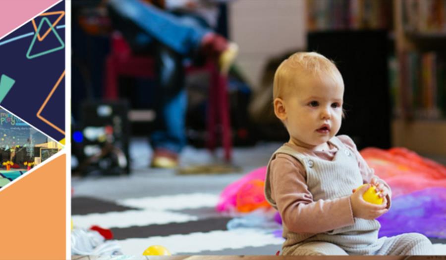 baby sat on the floor holding a yellow ball