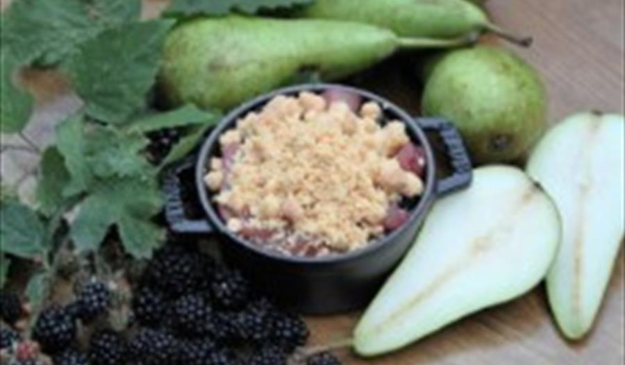 Backed pot with handles surrounded by pears and blackberries