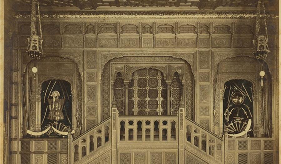 black and white photo of a carved hall with horns and armour on display
