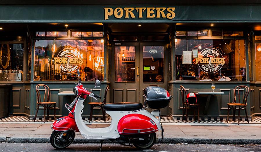 Exterior of Porters Wine Bar with gold handpainted sign and a moped scooter in front.