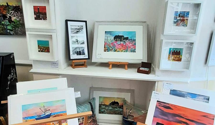interior photograph of art gallery showing prints in cradle and in frames on white wall
