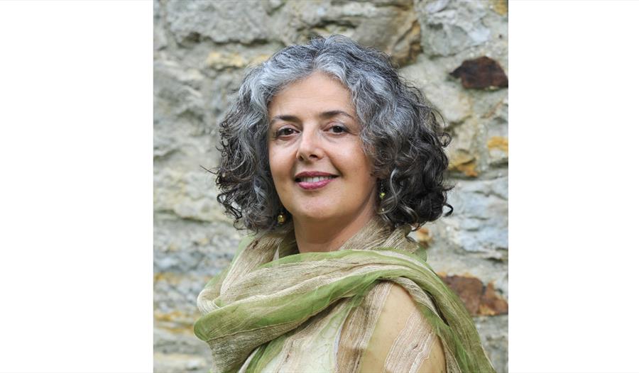 a photograph of a woman against an old brick wal, wears green silk shawl.