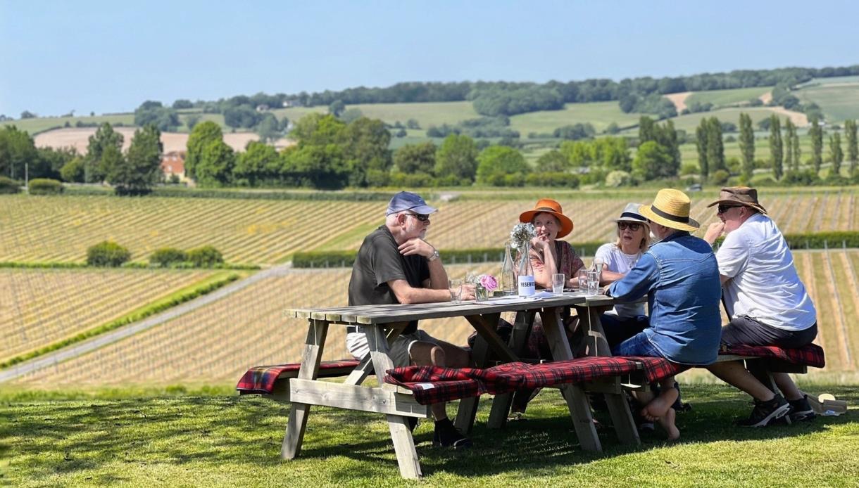 Visitors enjoying outdoor dining at the Winchelsea Gastronomic Promenade, overlooking vineyards and rolling countryside.