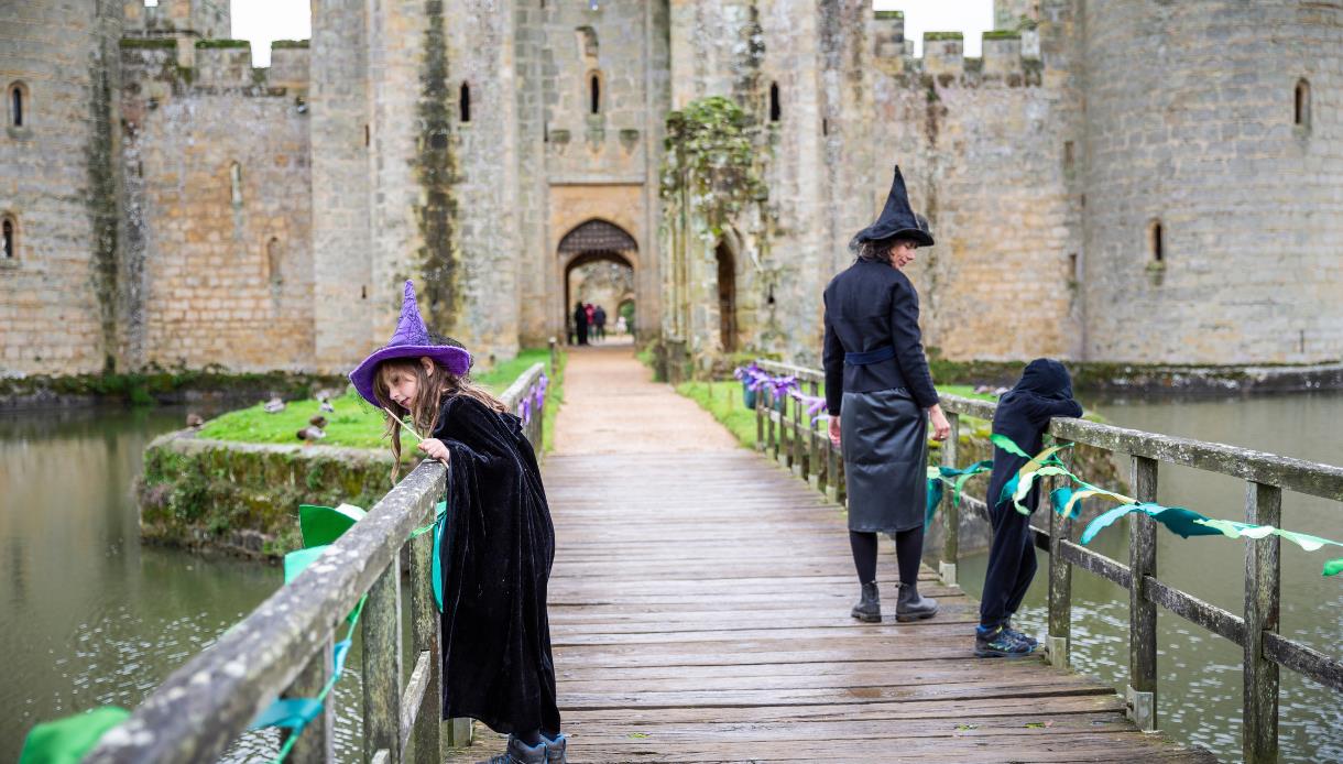 Children in witch costumes explore the bridge to Bodiam Castle during the Spell Quest family trail.