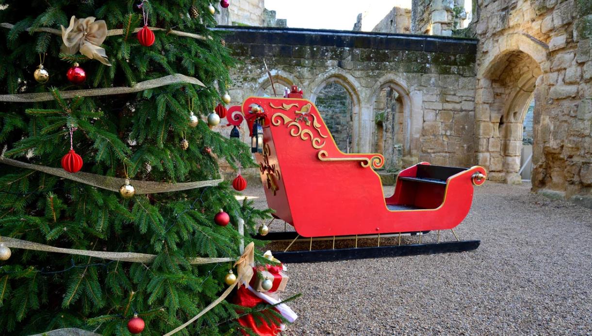 Christmas at Bodiam Castle with a decorated tree and festive sleigh set among historic medieval stone ruins.