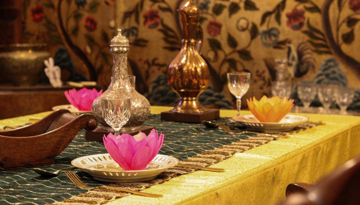 Festive Diwali dining table at Bateman’s with lotus decorations, glassware and gold-toned table settings.