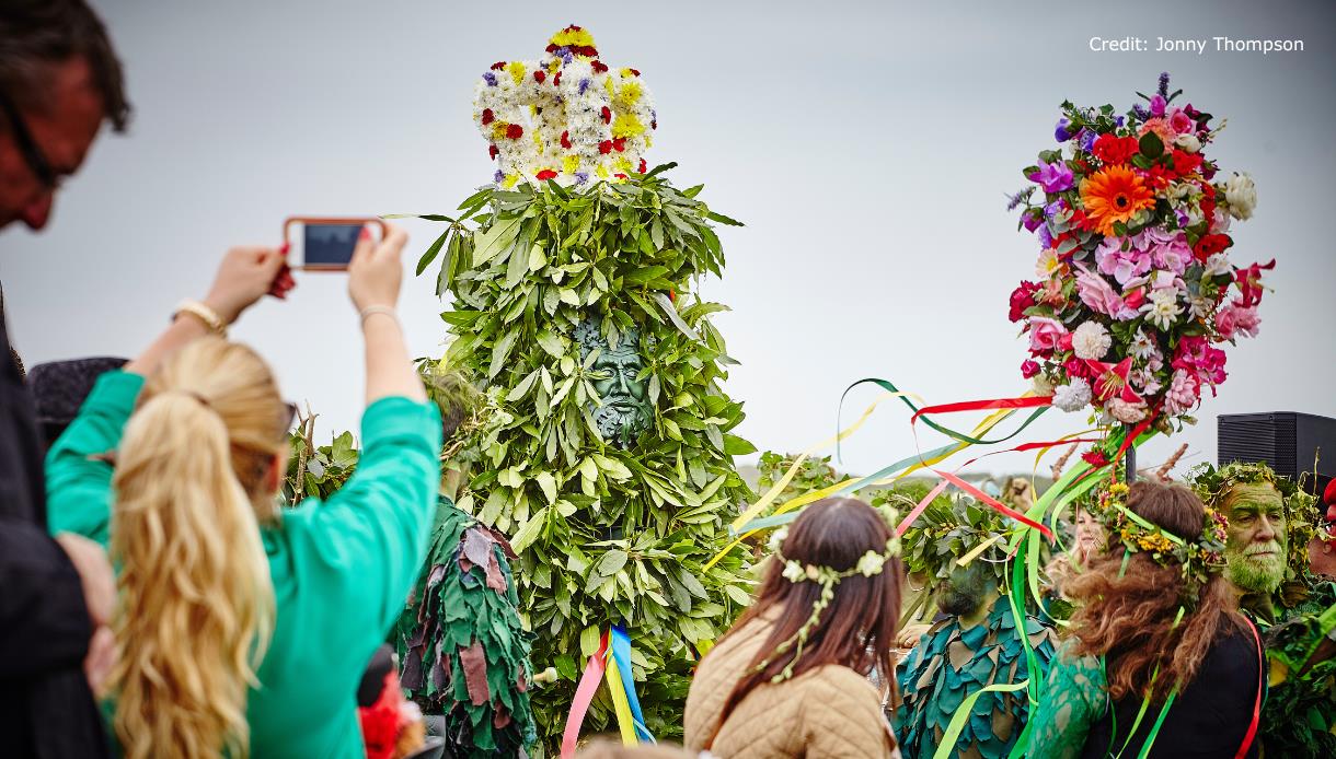 Jack in the Green figure covered in leaves and flowers surrounded by crowds during the Hastings Jack in the Green festival.