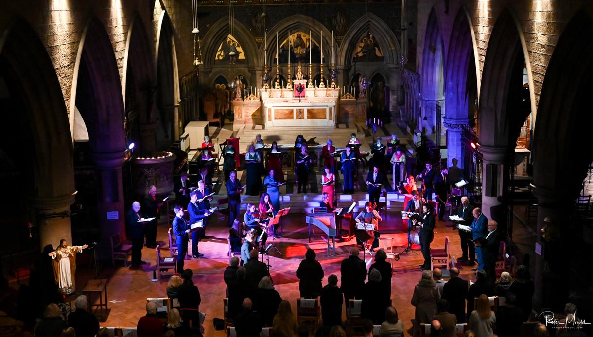 Singers of Hastings Philharmonic Orchestra on stage under coloured lights.