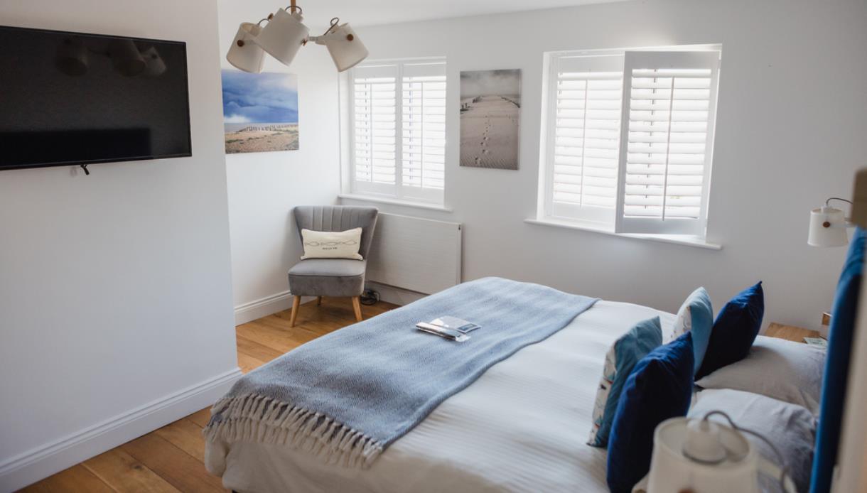 Modern ensuite bedroom at The Regent, Rye, featuring a king-size bed, armchair and wall-mounted TV.