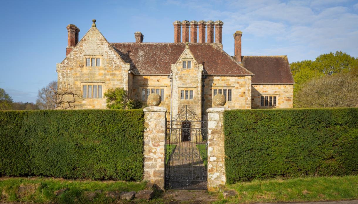 Bateman’s, Rudyard Kipling’s former home, viewed through a wrought-iron gate and clipped hedges.