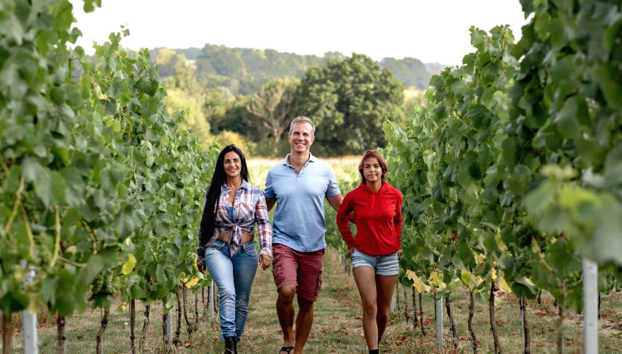 Oastbrook owners walking through vineyard rows surrounded by rolling countryside.