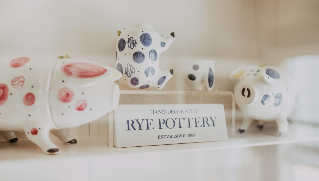 Hand-decorated Rye Pottery ceramics and pig-shaped ornaments displayed on a shop shelf in Rye.