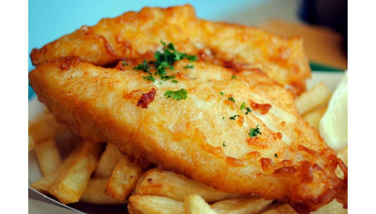 Crispy battered fish served on top of thick-cut chips with a sprinkle of parsley.