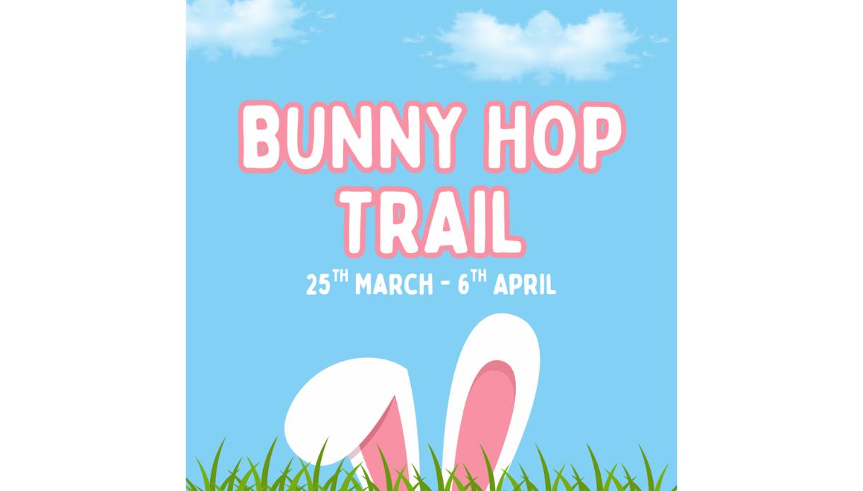Poster with text ‘Bunny Hop Trail, 25th March–6th April’ above bunny ears poking up from grass against a blue sky.