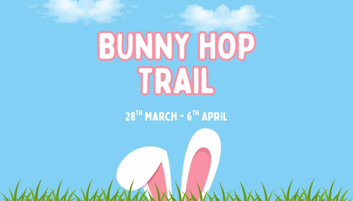 Poster with text ‘Bunny Hop Trail, 28th March–6th April’ above bunny ears poking up from grass against a blue sky.