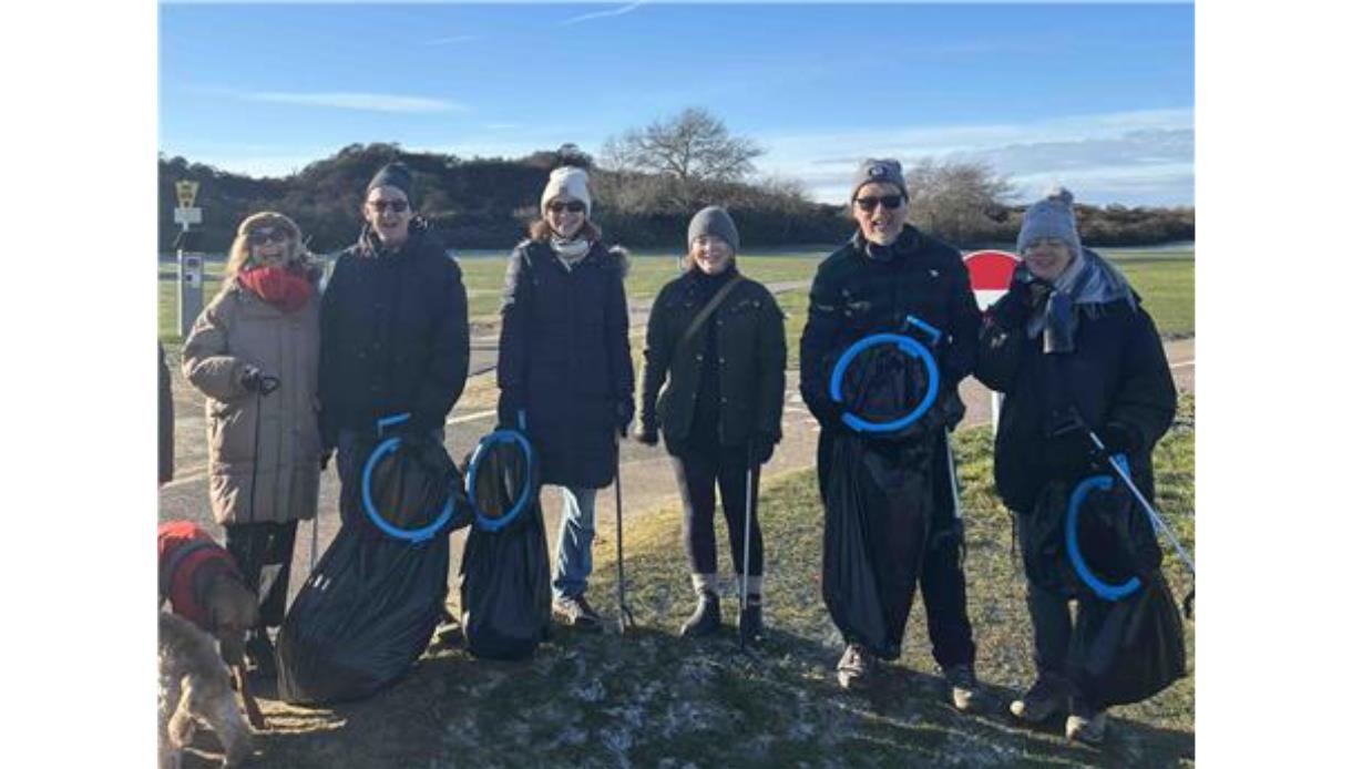 Group holding litter pickers and full trash bags during a community beach clean at The Gallivant in Camber.