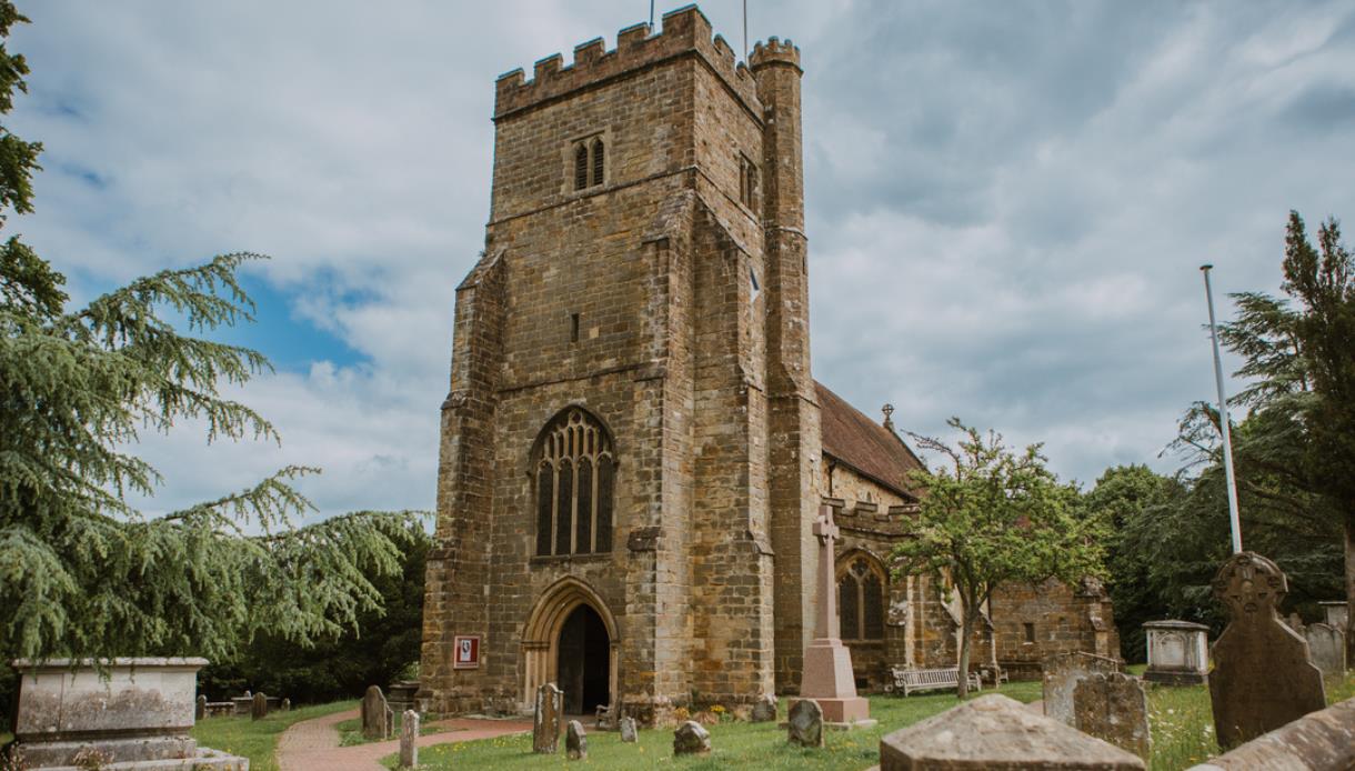 St Mary’s Church, Battle, with medieval stone tower, churchyard monuments and dramatic cloudy skies.