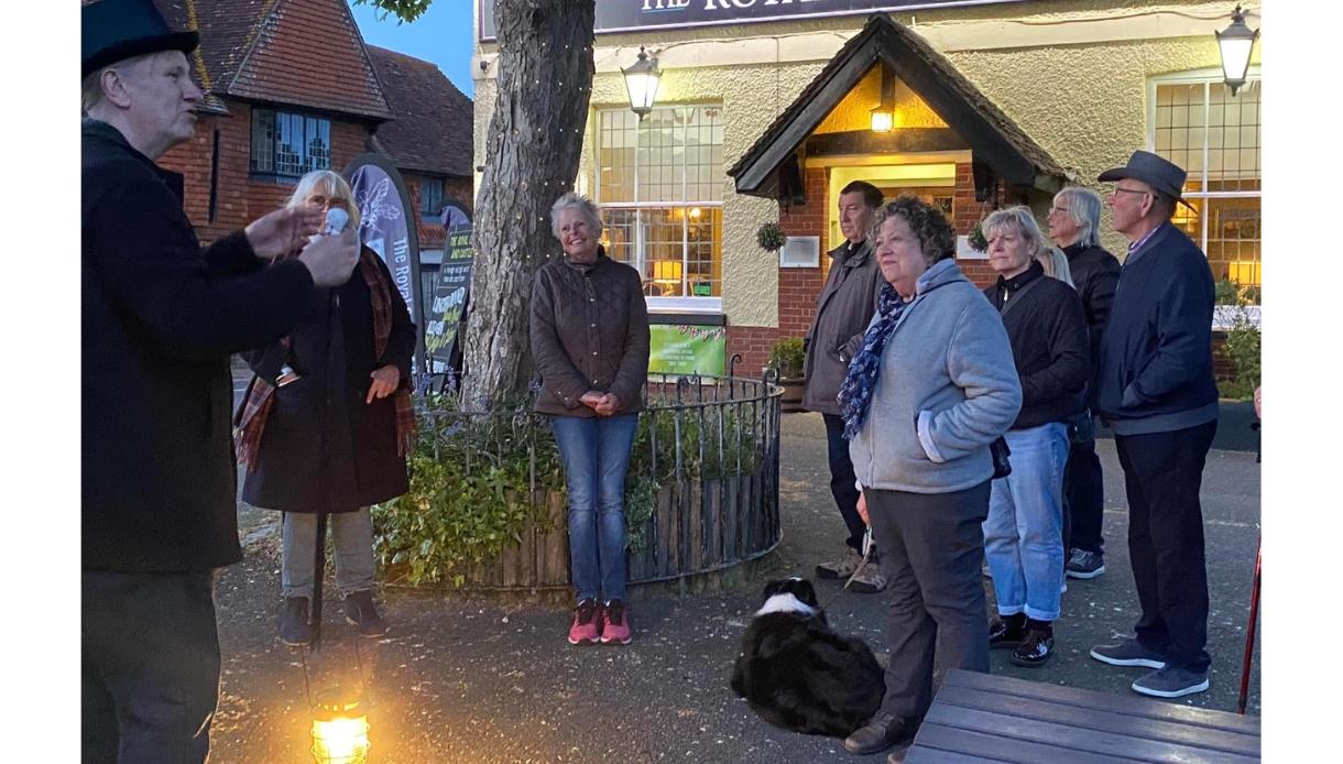 Guided ghost walk group gathered outside the Royal Oak & Castle Inn in Pevensey at dusk with lantern light.